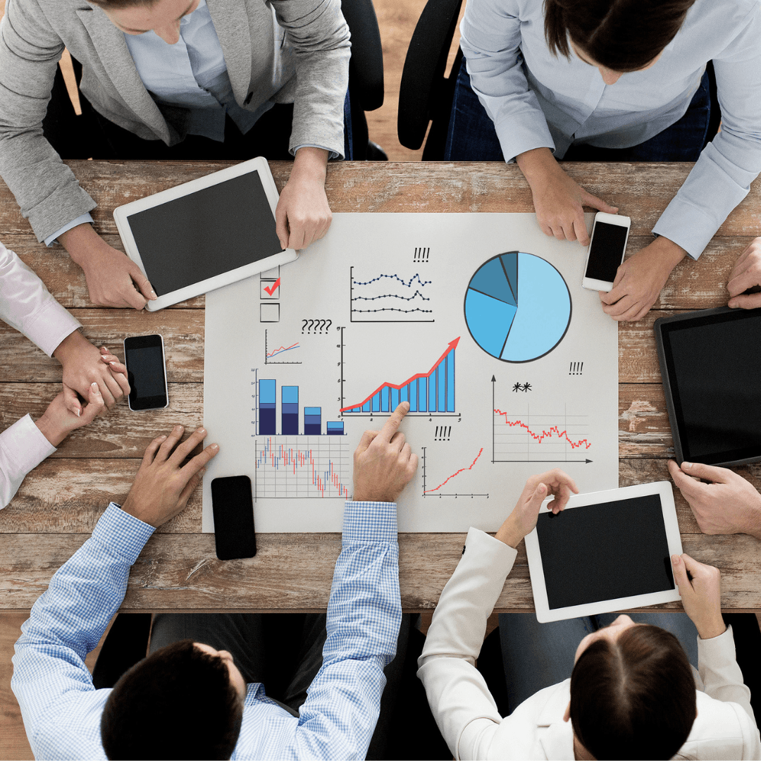 A group of business professionals sit around a table, analysing data.