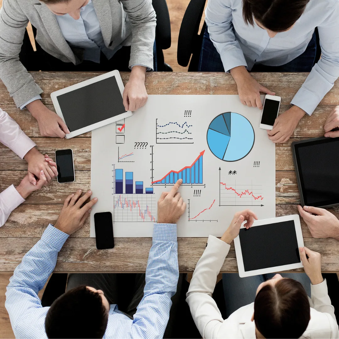 A group of business professionals sit around a table, analysing data.