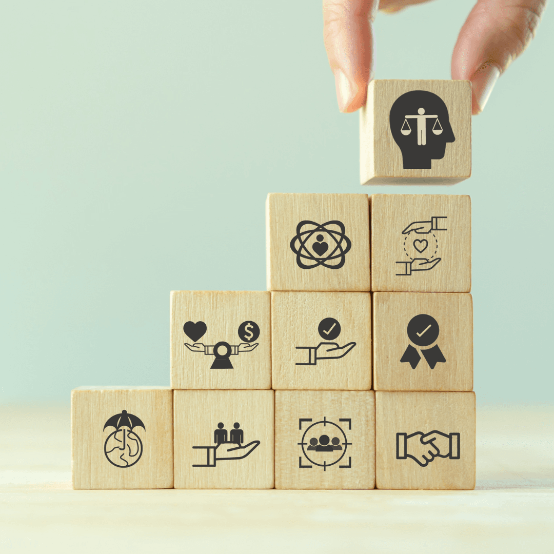 Hand placing a block atop a pyramid symbolising ethics, teamwork and shared values.